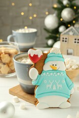 Delicious cookie in shape of snowman, cup with cocoa and Christmas decor on white wooden table