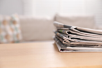 Stack of newspapers in different languages on table indoors. Space for text