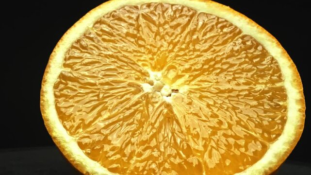 A Macrography capture of an orange slice, placed against a sleek, isolated black backdrop, unfolds as a visual masterpiece of citrus allure. A slice of orange with black background. Comestible.