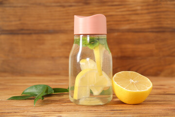 Sports bottle of infused water with lemon and mint on wooden background