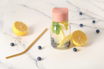 Sports bottle of infused water with blueberries and lemon on white background