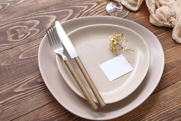 Stylish modern table setting with card on brown wooden background