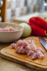 Pieces of chicken fillet on a cutting board and in a bowl on the table