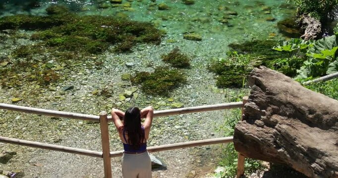 Girl in Blue Eye Natural Water Spring in Albania. Crystal Clear Water with Green Plants, aereal drone view