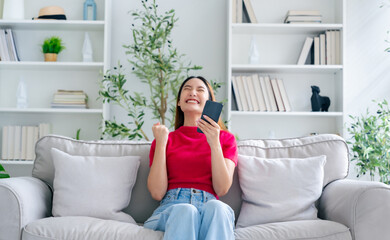 Happy young asian woman relax on comfortable couch at home texting messaging on smartphone, smiling girl use cellphone, chatting online message, shopping online from home