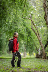 Photographer in a Red Jacket Capturing Nature's Beauty with a Camera in a Lush Green Forest