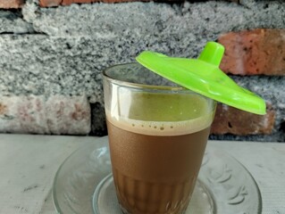Luwak coffee is still hot in a transparent glass cup with a green glass lid