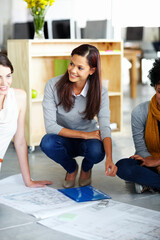 Woman, architect and team on floor with documents, blueprint or planning at property agency. People, sketch or design with paperwork in discussion, scrum or diversity in office at real estate company