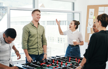 Happy people, foosball and office with game for team building, playing or bonding together. Young, group or employees enjoying fun competition, board challenge or football entertainment at workplace