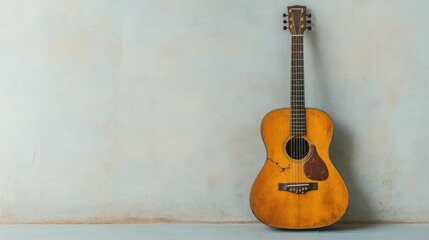 Fototapeta premium An old guitar with broken strings leaning against a wall, silence, the end of creativity and expression