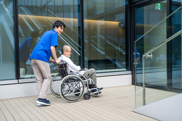 階段で困る車いすに座るシニアと介護施設スタッフ