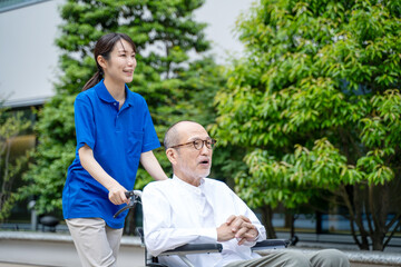 車いすのシニア男性と介護施設スタッフ