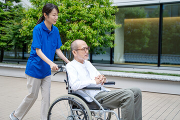 車いすのシニア男性と介護施設スタッフ
