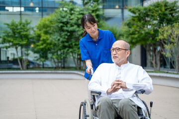車いすのシニア男性と介護施設スタッフ