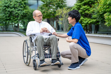 車いすのシニア男性と介護施設スタッフ