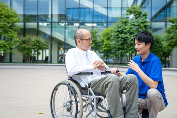 車いすのシニア男性と介護施設スタッフ