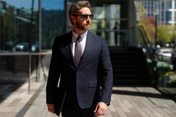 Old business man standing outdoor on modern office building. Business success. Business man thinking outdoor. Modern businessman in full suit standing outdoors near office cityscape.