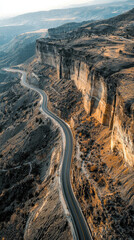 Aerial view of highway snaking through rocky terrain, showcasing stunning landscape and winding road. scene evokes sense of adventure and exploration