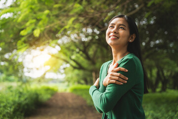confident asian woman embraces self-love, standing peacefully in serene park at sunset. joyful...