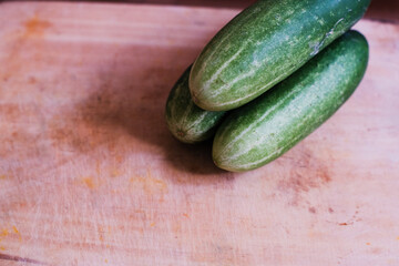Pile of Fresh cucumbers on a wooden cutting board, natural presentation, possibly in preparation for slicing or cooking.