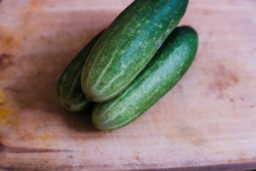 Pile of Fresh cucumbers on a wooden cutting board, natural presentation, possibly in preparation for slicing or cooking.