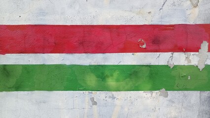 A green and red striped wall with a white stripe The wall is covered in graffiti.