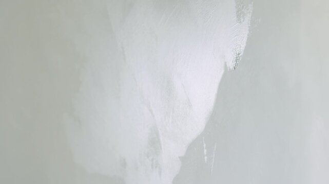 Slow motion handheld closeup worker applying decorative concrete plaster on the wall