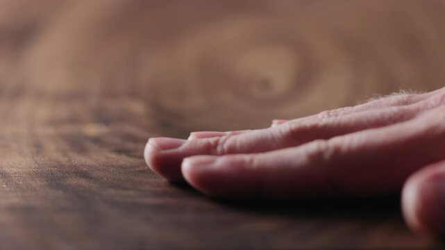 Slow motion man hand touch oil finished black walnut wood surface