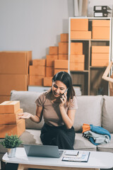 Asian SME business women use laptop computer checking customer order online shipping boxes at home....