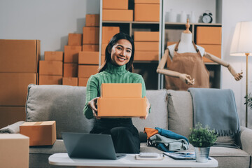 Asian SME business women use laptop computer checking customer order online shipping boxes at home....