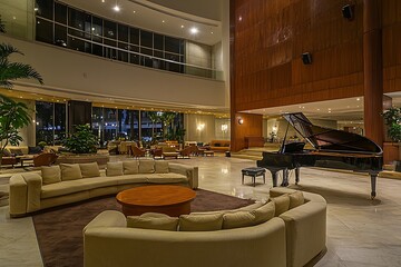 Broad hotl lobby quippd with comfortabl sofas and a grand piano.