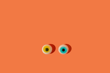 Spooky Halloween concept, two eyeballs on orange background.