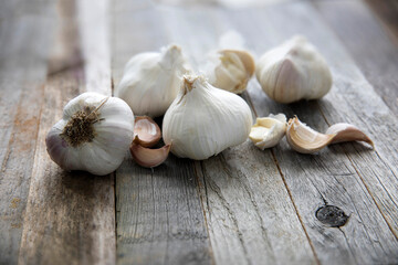 Fresh garlic heads and cloves hover over a wooden table. Fresh peeled garlic and bulbs