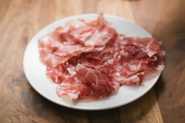dried coppa ham on white plate
