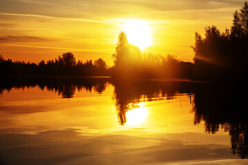 Obraz premium Spring sunrise over the northern smooth water river. Trees with budding foliage, spring clothes the land with verdure