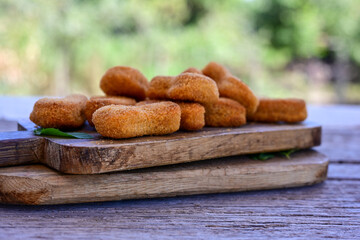 
 Crispy oven baked  chicken nuggets and ketchup. Breaded chicken fillets  with chilly peppers and fresh basi on wooden rustic background