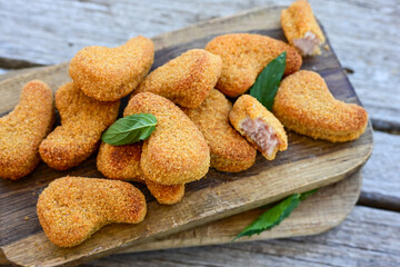 
 Crispy oven baked  chicken nuggets and ketchup. Breaded chicken fillets  with chilly peppers and fresh basi on wooden rustic background