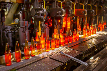 Glass factory, production of glass containers. Molten glass is blown into molds. Robotics in...