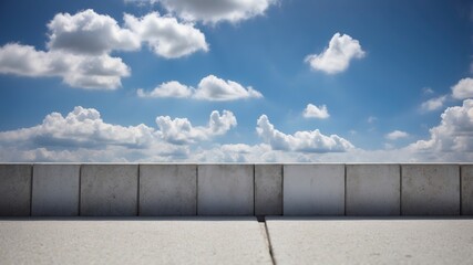 Obraz premium A bright blue sky with fluffy white clouds above a gray concrete wall.