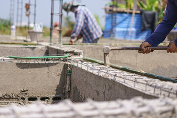 Construction worker hammering a concrete form at a building site, reinforcing the foundation structure.