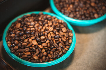 Close-up of roasted coffee beans in green bowls placed on a counter.