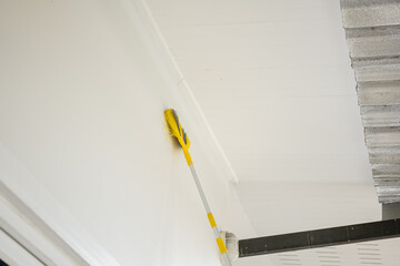 Cleaning high walls with a long-handled brush in a house.