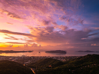 A breathtaking panoramic view of a vibrant sunrise casting warm hues over a coastal town, with the...