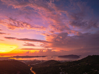 A breathtaking panoramic view of a vibrant sunrise casting warm hues over a coastal town, with the...