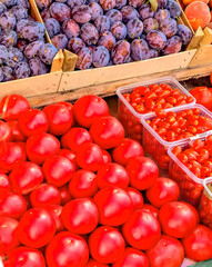 Fresh, bright products on the market are plums, tomatoes, strawberries. Colorful assortment of vegetables and fruits on the counter, Vertical