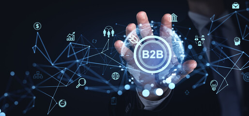 Businessperson interacting with B2B digital interface network, showcasing various icons and data points on a dark background.