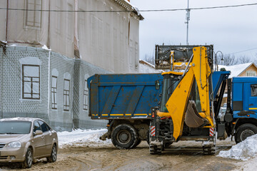 A blue dump truck is parked in front of a building