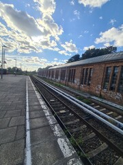 Fototapeta premium Blick auf Bahngleise mit einem alten, zerfallenen Gebäude und einem wolkigen Himmel in Bernau bei Berlin (Brandenburg)