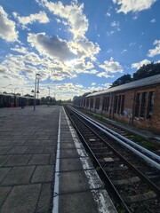 Fototapeta premium Blick auf Bahngleise mit einem alten, zerfallenen Gebäude und einem wolkigen Himmel in Bernau bei Berlin (Brandenburg)
