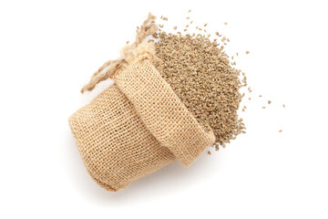 Close-up of Dry Organic Carom seeds (Trachyspermum ammi) or Ajwain, spilled out from a laying jute bag. Isolated on a white background.